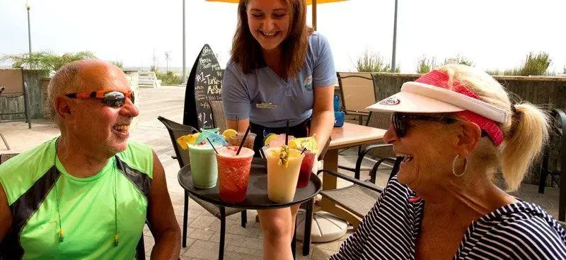 A waitress bringing a couple cocktails.