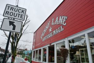 A sign for a truck route in front of Penny Lane Antique Mall.
