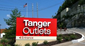 A red entrance sign for Tanger Outlets.