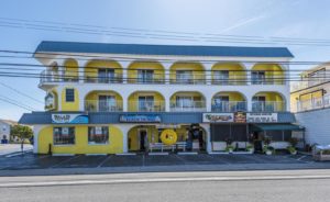 A yellow and white motel building with shops on the first floor.