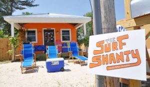 Blue beach chairs in front of an orange surf shanty.