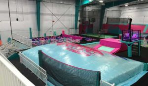 A trampoline park with a blue and pink indoor trampoline.